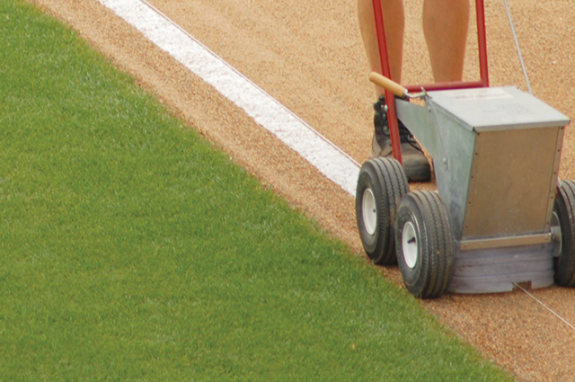White line chalk being added to a softball field.